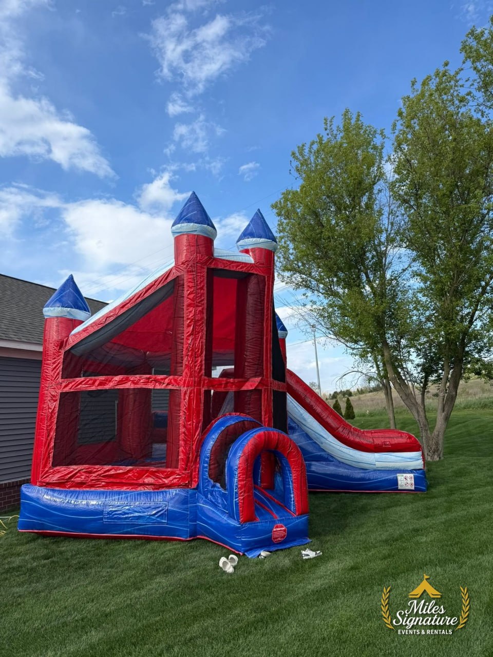 Red and blue bounce house with slide set up on a lawn